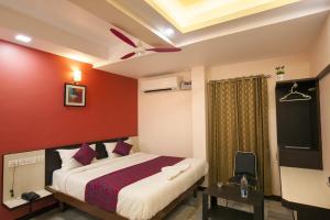 a bedroom with a bed and a red wall at Hotel Lotus in Madurai