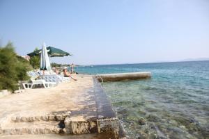 a beach with chairs and an umbrella in the water at Apartment Put Draga in Kožino