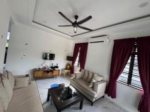 a living room with a couch and a ceiling fan at Student Homestay in Kampong Ru Sepuloh