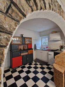 a kitchen with a checkered floor and a stone wall at Le gîte d'alfred in Prades