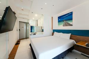 a bedroom with a white bed and a flat screen tv at Hamdeok Beach Stay Jeju in Jeju