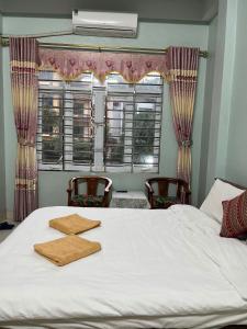 a bedroom with a white bed with two chairs and a window at Sunshine Loop Hostel in Làng Lap
