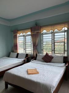 two beds in a room with two windows at Sunshine Loop Hostel in Làng Lap