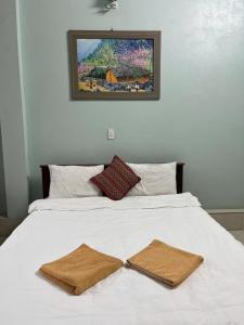 a white bed with two brown towels on it at Sunshine Loop Hostel in Làng Lap