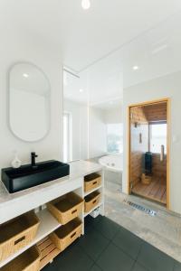 a white bathroom with a sink and a mirror at Villala Fibana in Motobu