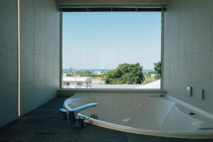 a bath tub in a room with a large window at Villala Fibana in Motobu