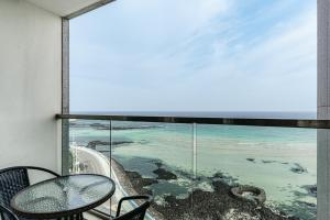 a balcony with a table and a view of the ocean at Hamdeok Beach Stay Jeju in Jeju