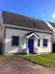 une petite maison blanche avec une porte bleue dans l'établissement Glendale Chestnut Grove, à Rosslare