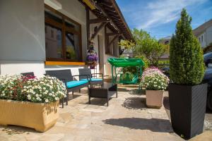 a patio with chairs and potted plants and flowers at Hôtel Le Divona in Divonne-les-Bains