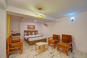 a bedroom with a bed and chairs in a room at FabHotel Shree Ji in Lucknow