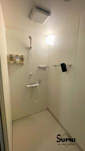 a bathroom with a shower with a light on the wall at ましこのま- 明治の建物をリノベした街中ローカルステイ in Mashiko