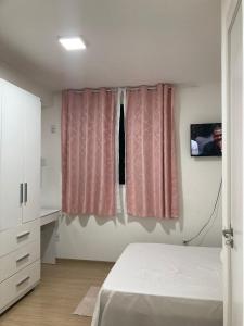 a bedroom with a bed and a window with pink curtains at Hostel Vibes in Rio de Janeiro
