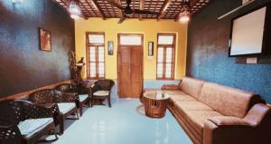 a living room with a couch and chairs and a television at Pepper Valley Resort in Kalpetta