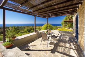 a patio with a table and chairs and the ocean at Villa Theodora in Lakíthra