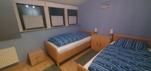 a bedroom with two beds and a chair and windows at Ferienwohnung Hahnentange in Rhauderfehn