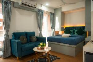 a living room with a blue couch and a bed at NEON - Nirvana Stays With PVT Balcony -1 Km from Airport in Pune