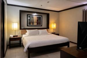 a bedroom with a bed and two lamps and a tv at O Hotel in Bacolod +12 photos