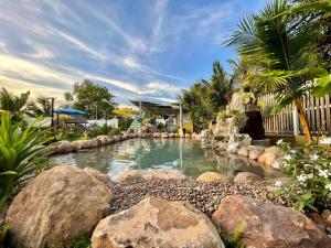 a swimming pool with rocks in a backyard at Vvillage in Phumĭ Balăng