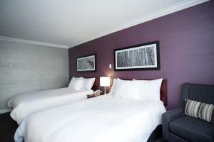 a hotel room with two beds and a chair at Sandman Hotel & Suites Williams Lake in Williams Lake +31 photos