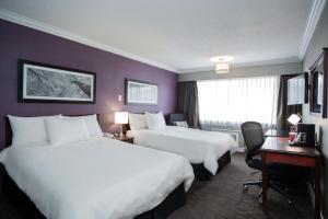 a hotel room with two beds and a desk at Sandman Hotel & Suites Williams Lake in Williams Lake