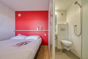 a bedroom with a red accent wall and a toilet at UNISOTEL Le Havre in Le Havre