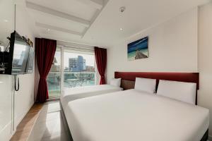 a hotel room with two beds and a window at Hamdeok Beach Stay Jeju in Jeju