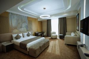 a hotel room with a large bed and a couch at Grand Altyn Hotel in Shymkent +67 photos