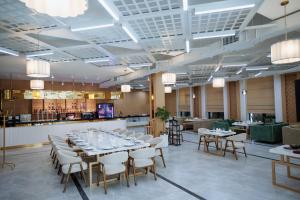 a dining room with tables and chairs and a bar at Grand Altyn Hotel in Shymkent