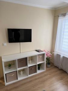 a white entertainment center with a flat screen tv on a wall at Gemütliches Appartement 5 - mit Küche und Bad zur Eigennutzung -Schuster Homes- in Vechelde