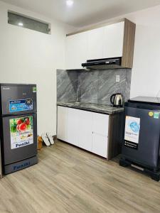 a kitchen with white cabinets and a black refrigerator at sentosa apartments in Dien Ban