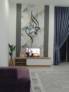 a living room with a tv and a couch at FAs KLIA Guesthouse, 4BR 4 AC , NEAR KLIA, NILAI in Sepang