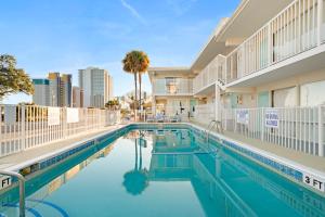 a pool at a hotel with a palm tree and buildings at Fin's Inn & Suites in Myrtle Beach