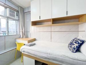 a small bedroom with a bed and a yellow chair at 利園賓館 in Hong Kong