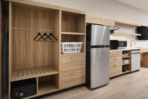 a kitchen with a refrigerator and wooden cabinets at Hyatt Studios Huntsville in Huntsville