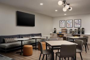 a waiting room with tables and a couch and a tv at Hyatt Studios Huntsville in Huntsville
