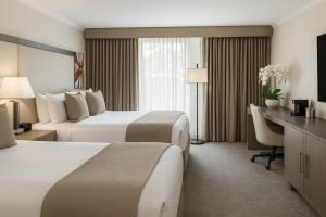 a hotel room with two beds and a desk at Ontario Airport Hotel & Conference Center in Ontario