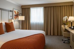 a hotel room with a large bed and a desk at Ontario Airport Hotel & Conference Center in Ontario