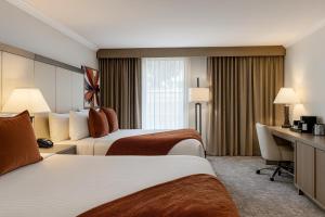 a hotel room with two beds and a desk at Ontario Airport Hotel & Conference Center in Ontario