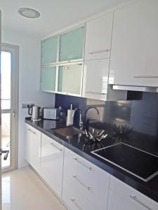 a kitchen with white cabinets and a black counter top at Vista Bella Apartment in Calpe