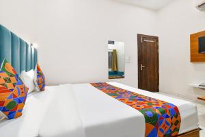 a bedroom with a white bed with a colorful blanket at FabHotel Olive Inn in Indore +32 photos