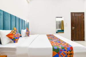 a bedroom with a large bed with colorful pillows at FabHotel Olive Inn in Indore