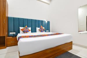 a bedroom with a large white bed with a blue headboard at FabHotel Olive Inn in Indore