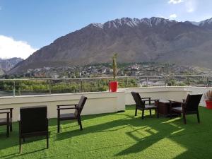 a patio with chairs and a table with a view of a mountain at Hotel The White Castle Kargil in Kargil