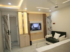 a room with a bed and a tv and a couch at Happy Residency in Patna