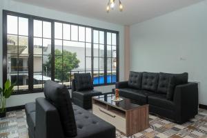 a living room with black furniture and large windows at Urbanview Grand Lotus Hotel by RedDoorz in Purwokerto