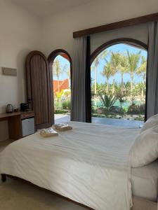 a bedroom with a bed and a window with palm trees at Arabian Coral in Ḩaḑbaram