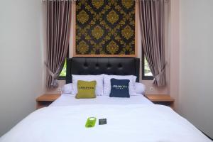 a bedroom with a white bed with two pillows at Urbanview Grand Lotus Hotel by RedDoorz in Purwokerto