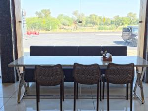 a table with three chairs in front of a window at Hotel Keshav in Dhorīmanna