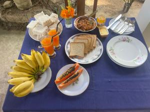 a blue table with plates of food and bananas and bread at Dew home stay in Dickwella +8 photos