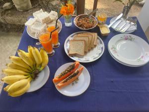 a blue table with plates of food and bananas and bread at Dew home stay in Dickwella